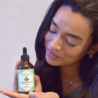Woman holding a bottle of SIVA Peppermint Oil with a dropper.